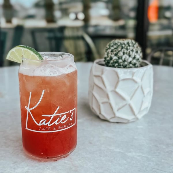 Katie's Cafe & Bakery branded drink with a lime wedge next to a small potted cactus.