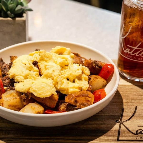 Breakfast bowl with scrambled eggs, potatoes, and peppers, next to an iced tea from Katie's Cafe & Bakery.